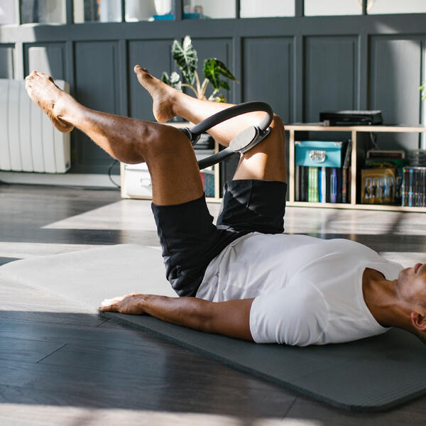 Aro de pilates DOMYOS en uso, tumbado sobre la esterilla